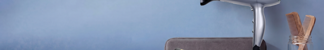 Hair dryer, flat iron, and comb on a blue background